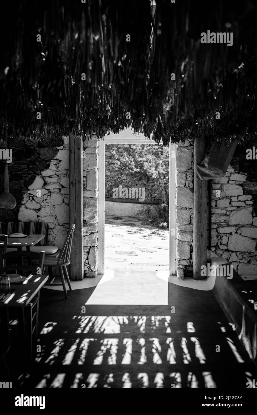 A grayscale vertical shot of the inside of a tropical cabin with bright sunlight coming in through the door Stock Photo