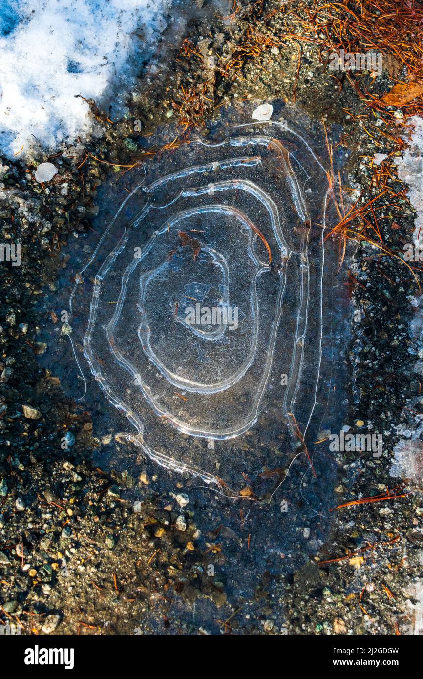 Circle rings in frozen ice water puddle with snow Stock Photo - Alamy