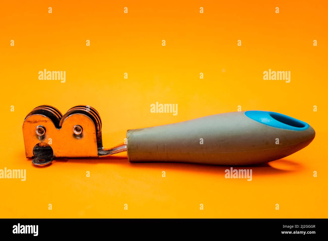 Knife sharpener isolated on an orange background. Inexpensive non-professional kitchen utensil. Stock Photo