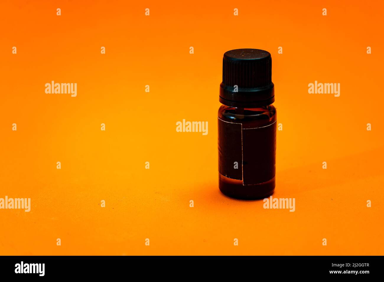 Small amber glass dropper bottle insulated on orange background. copy space. Stock Photo