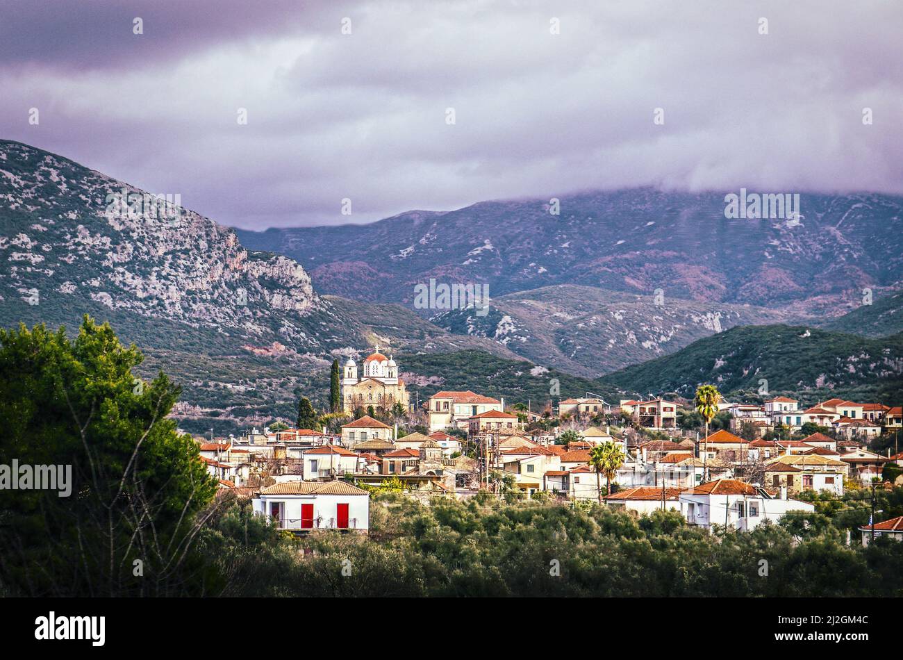 View down in valley at tile roofs of Greek village with large church in Taygetos Mountains between Kardamyli and Kalamata on Peloponnese Peninsula wit Stock Photo