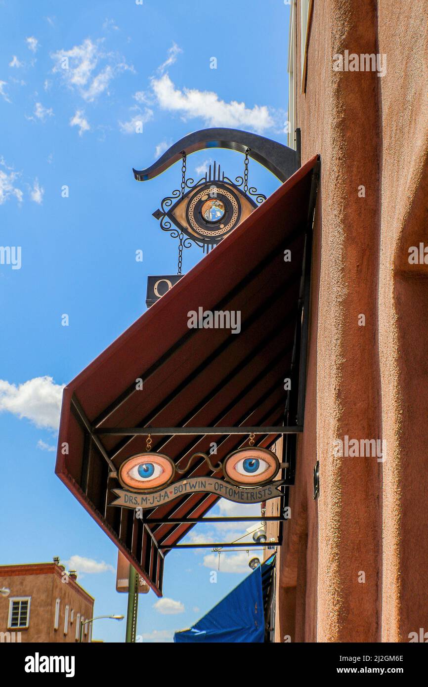 2017 07 19Santa Fe NM USA - Eyeball optometrist signs on street of Santa Fe NM - graphic and vintage against stark buildings and blue sk Stock Photo