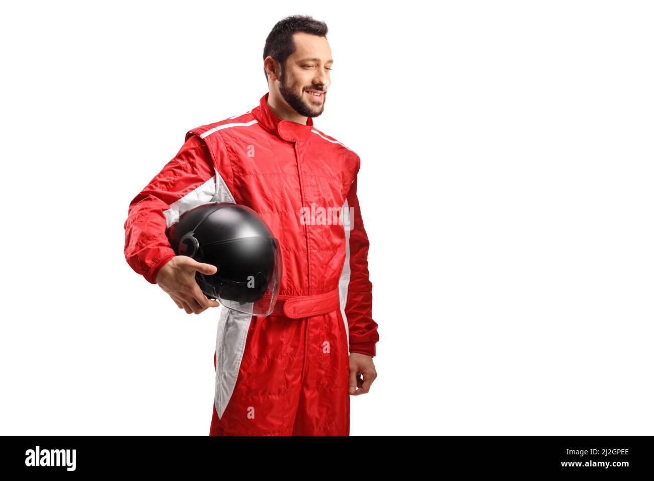 Smiling racer in a red suit holding a black helmet and looking to the side isolated on white background Stock Photo