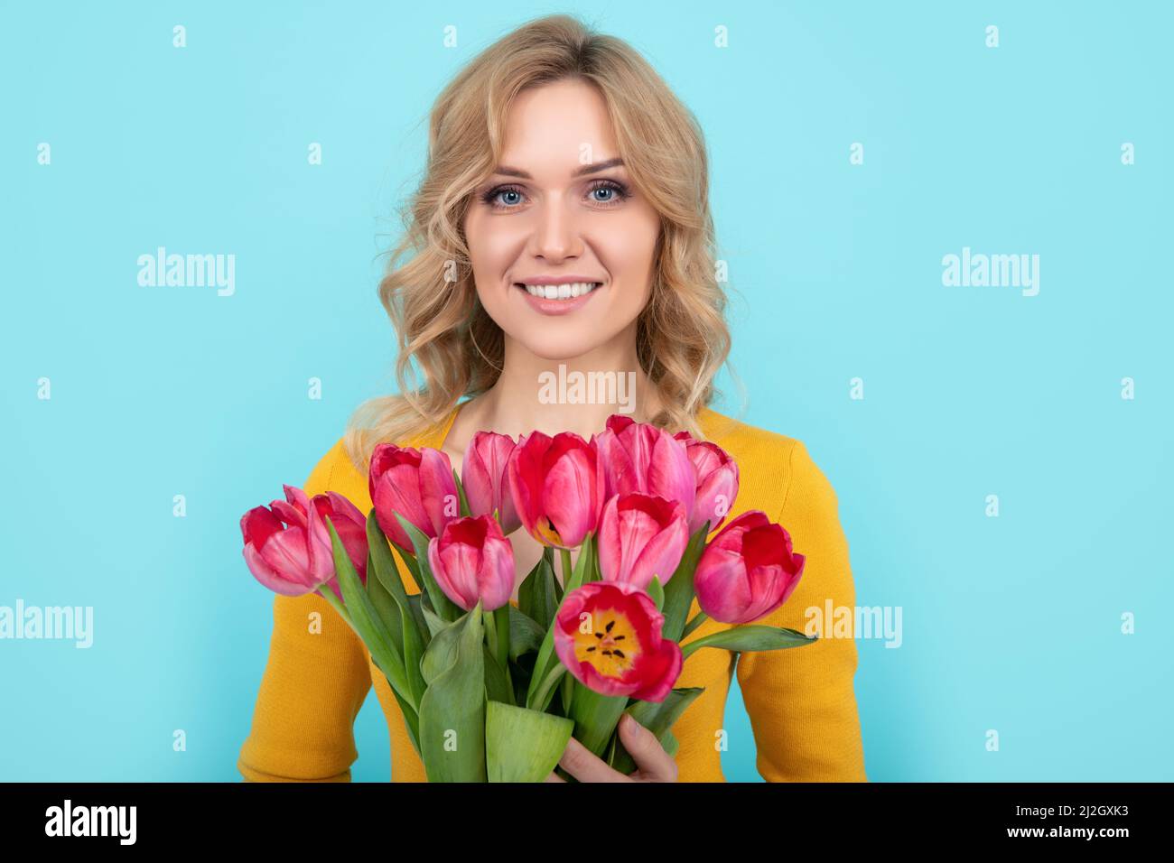 happy young woman with spring tulip flowers on blue background. march 8 Stock Photo