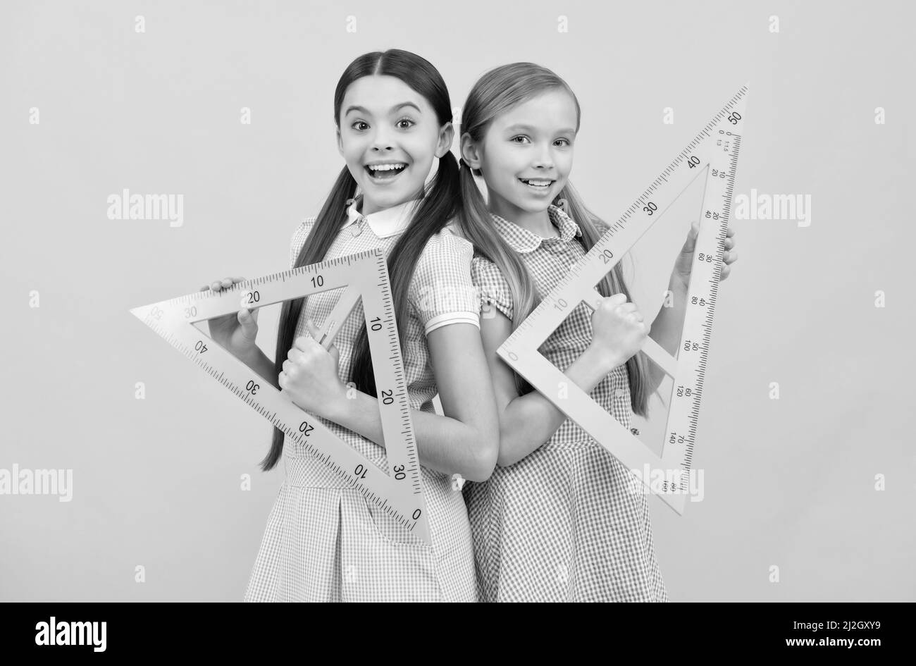 Education for all children. Happy teen girls hold triangular rulers. School education. Geometry lesson Stock Photo