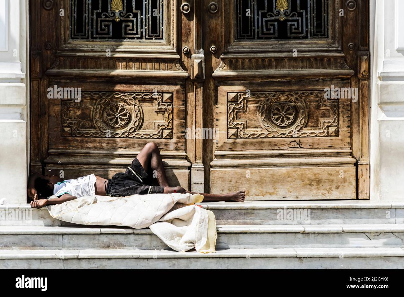 Homeless man sleeping at the door of a historic building in the city of Salvador, capital of Bahia, Brazil Stock Photo