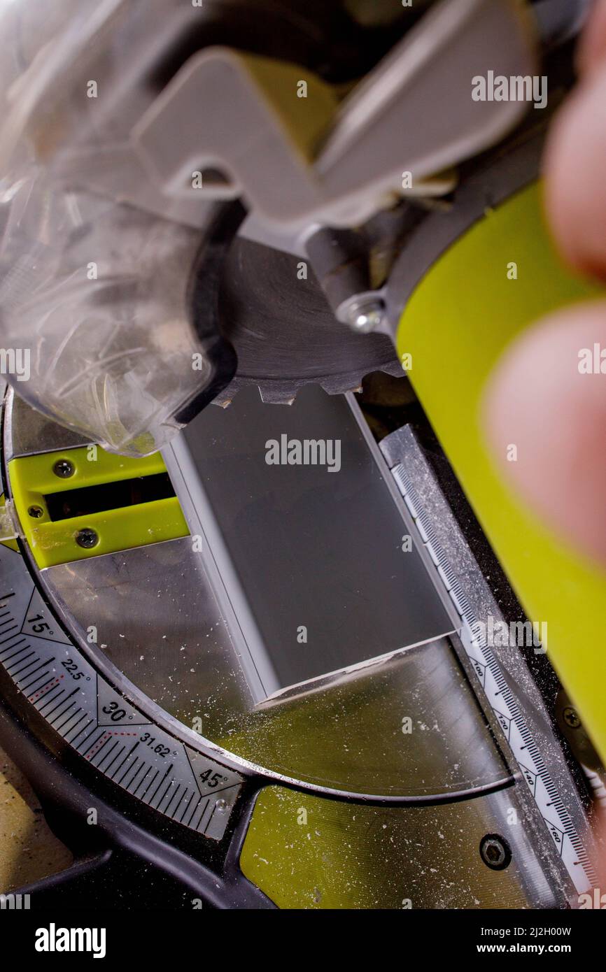 Worker cutting baseboard on the circular saw before installing Stock