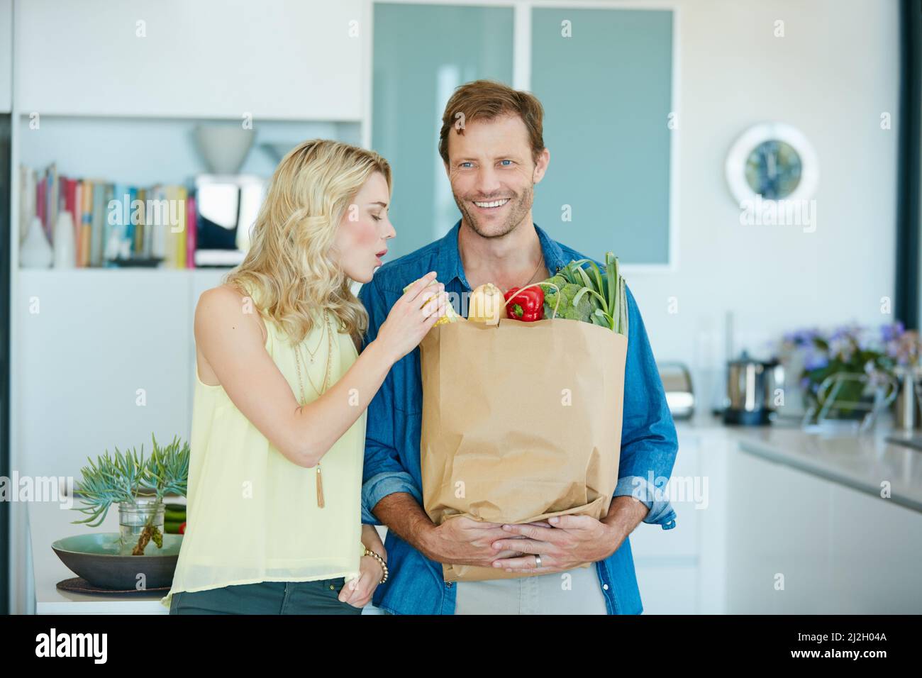 The healthy couple is a happy couple. Shot of a happy couple holding a bag full of healthy groceries at home. Stock Photo
