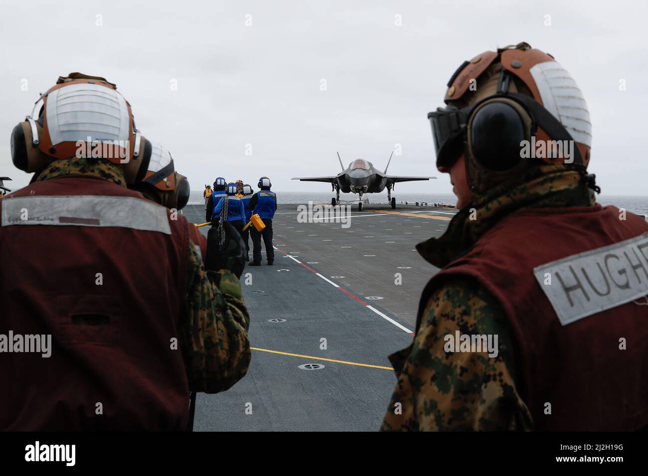 220331-N-CM110-1058 PACIFIC OCEAN (Mar. 31, 2022) – Marines assigned to Marine Aircraft Group 13 (MAG13), based out of Yuma, Ariz., watch as an F-35B Lightning aircraft taxies across the flight deck aboard amphibious assault ship USS Tripoli (LHA 7), Mar. 31. VMX-1 is embarked aboard Tripoli as part of the U.S. Marine Corps’ Lightning carrier concept demonstration. The Lightning carrier concept demonstration shows Tripoli and other amphibious assault ships are capable of operating as dedicated fixed-wing carrier platforms, capable of bringing fifth generation Short Takeoff/Vertical Landing air Stock Photo