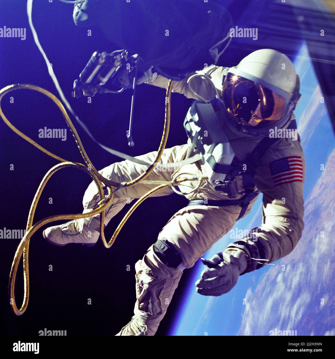 On June 3, 1965 Edward H. White II became the first American to step outside his spacecraft and let go, effectively setting himself adrift in the zero gravity of space. For 23 minutes White floated and maneuvered himself around the Gemini spacecraft while logging 6500 miles during his orbital stroll. White was attached to the spacecraft by a 25 foot umbilical line and a 23-ft. tether line, both wrapped in gold tape to form one cord. In his right hand White carries a Hand Held Self Maneuvering Unit (HHSMU) which is used to move about the weightless environment of space. The visor of his helmet Stock Photo