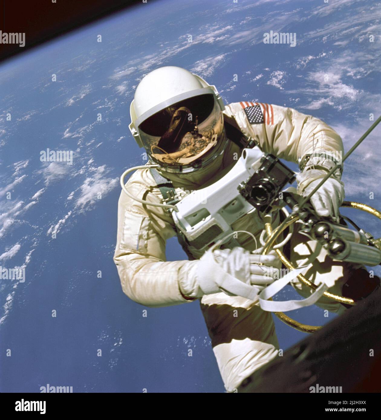 On June 3, 1965 Edward H. White II became the first American to step outside his spacecraft and let go, effectively setting himself adrift in the zero gravity of space. For 23 minutes White floated and maneuvered himself around the Gemini spacecraft while logging 6500 miles during his orbital stroll. White was attached to the spacecraft by a 25 foot umbilical line and a 23-ft. tether line, both wrapped in gold tape to form one cord. In his right hand White carries a Hand Held Self Maneuvering Unit (HHSMU) which is used to move about the weightless environment of space. The visor of his helmet Stock Photo