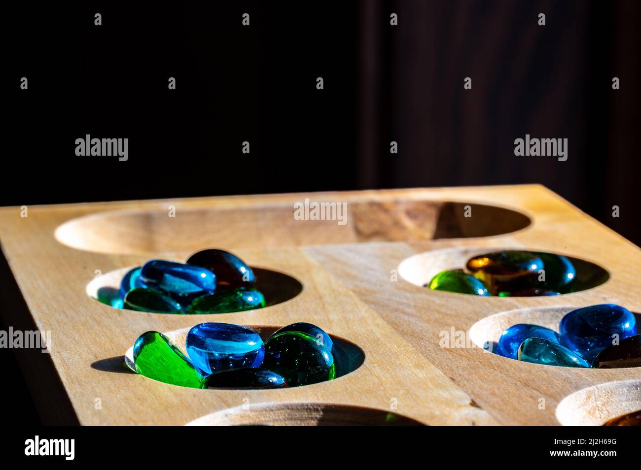 Selective focus on glass beads on a wooden mancala board Stock Photo