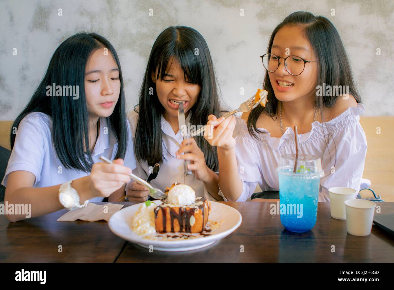 group of asian teenager eating sweet snack in coffee cafe Stock Photo