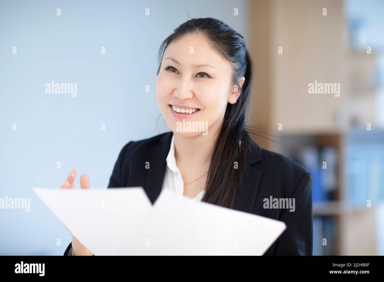 Smiling businesswoman with documents in office Stock Photo