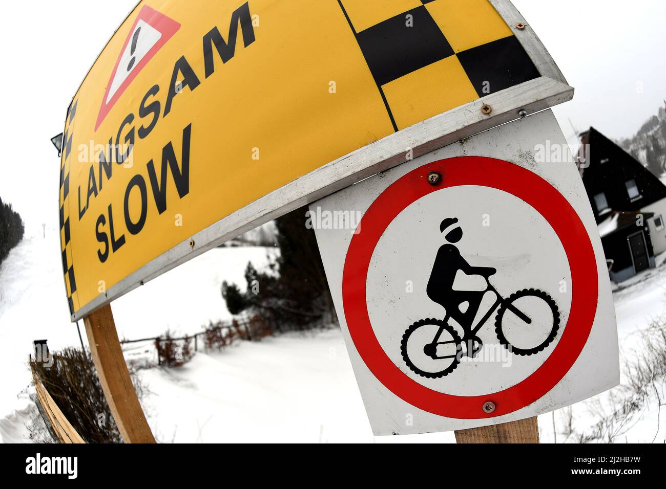 St. Andreasberg, Germany. 01st Apr, 2022. A mountain bike symbol is attached to the mountain bike park on the snow-covered Matthias Schmidt Mountain under the lettering 'Langsam'. After the end of the winter sports season, the Harz Mountains are getting ready for bike tourists. Credit: Swen Pförtner/dpa/Alamy Live News Stock Photo