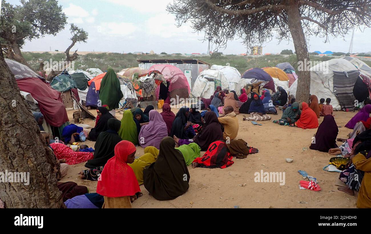 Mogadischu, Somalia. 29th Mar, 2022. Drought-affected people sit between huts at the Al-Hidaya camp for internally displaced people on the outskirts of the capital. Many of them slept on the road for several days to reach the camp. Credit: Mohamed Odowa/dpa/Alamy Live News Stock Photo