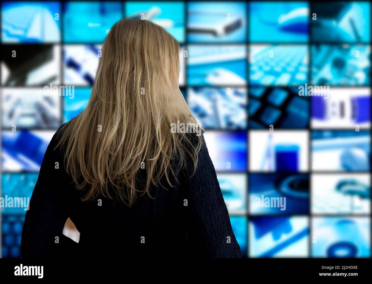 blond woman in front of panel screens showing technology themed images Stock Photo