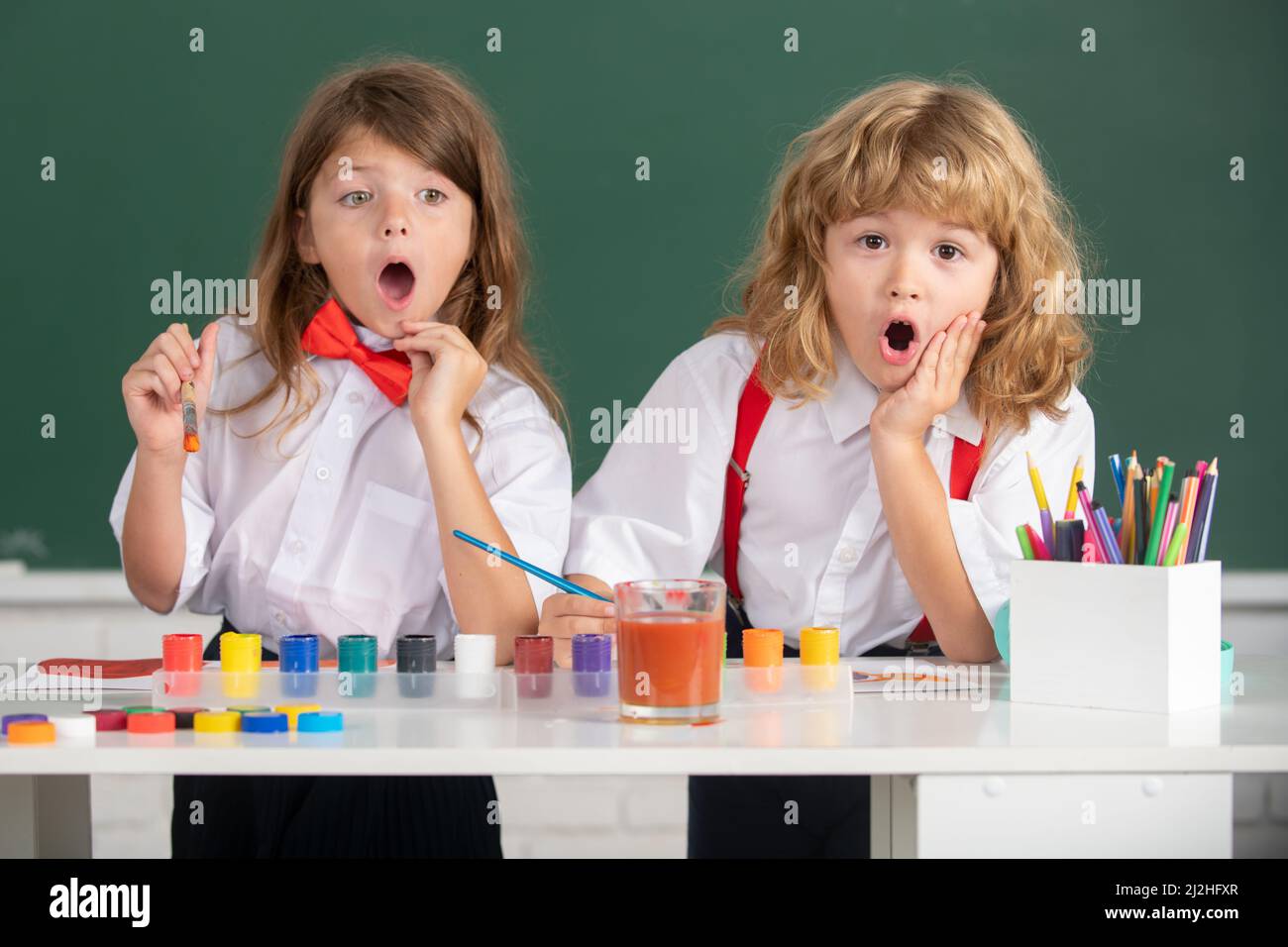 Cute school surprised friends kids drawing and painting at school. Friendly boy an girl funny pupils draw. Friendship in school. Childhood learning Stock Photo