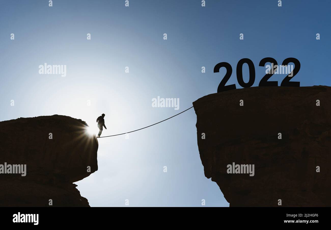 2022 new year concept, silhouette a man walking on rope to 2022 Stock Photo