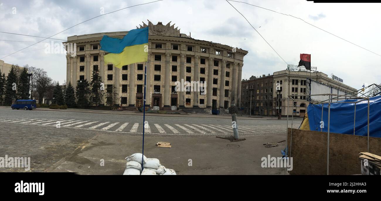 Central Administrative Building of Kharkiv, Ukraine, hugely damaged by the direct strike of russian missile, with the flag of Ukraine, and black/red flag of the Ukraine Rebellion Army. Stock Photo