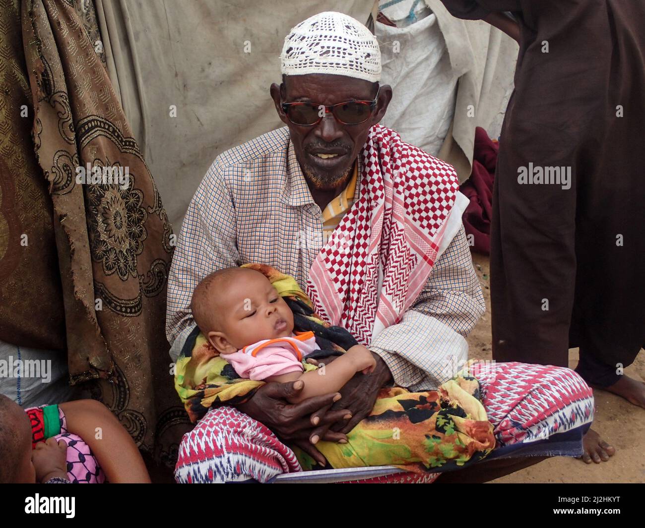 Mogadischu, Somalia. 29th Mar, 2022. Drought-stricken Saleeban Muse, a father of eight, holds his young daughter on his lap at the Al-Hidaya camp for internally displaced persons on the outskirts of the capital. Credit: Mohamed Odowa/dpa/Alamy Live News Stock Photo