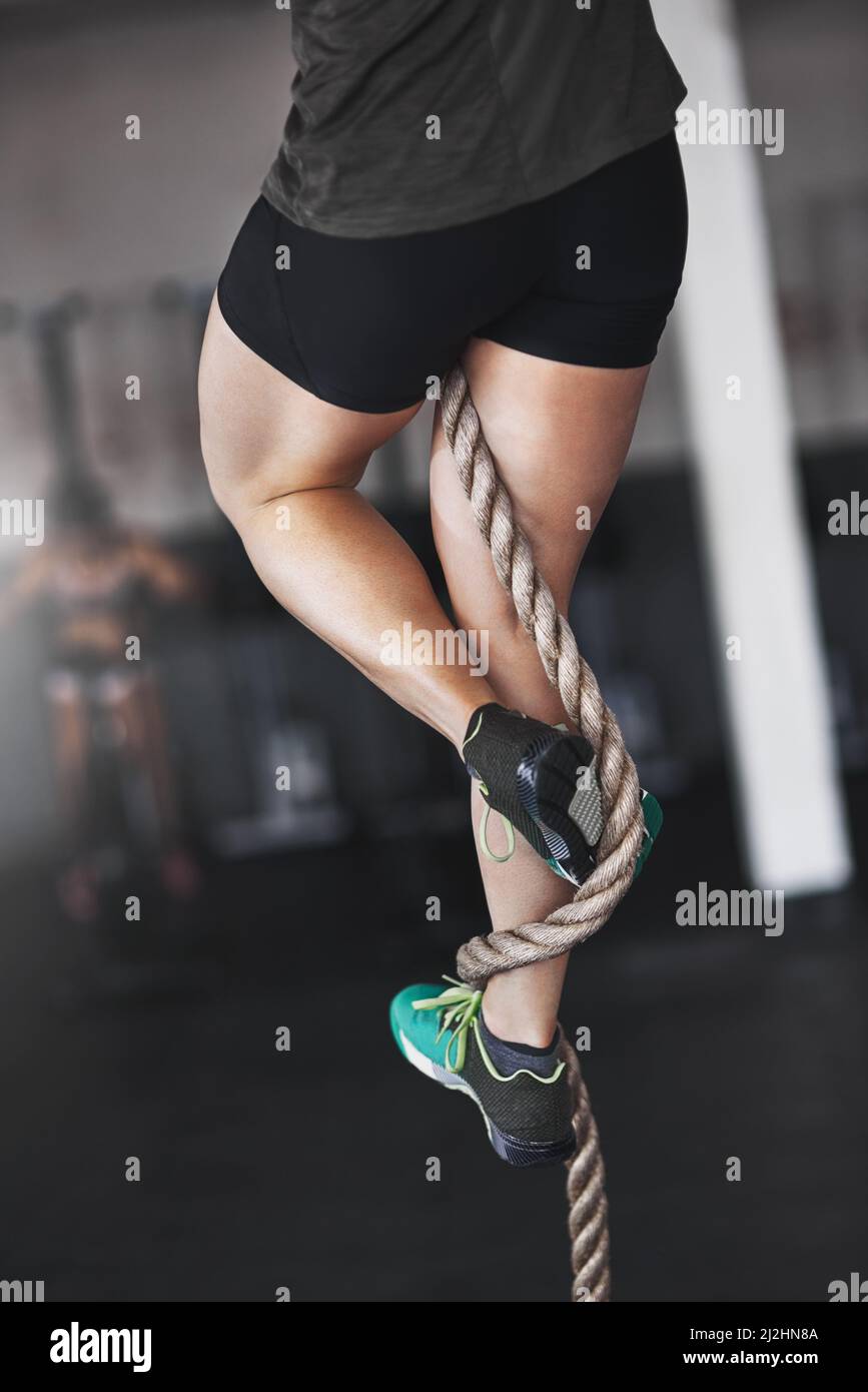 Getting a foothold. Cropped shot of a young woman climbing a rope at the gym. Stock Photo