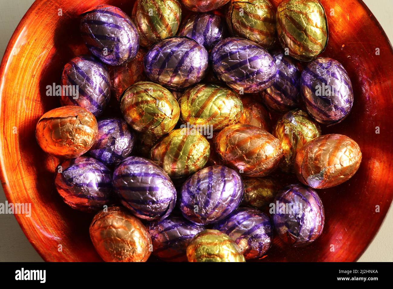 multi-colored wrapped chocolate easter eggs in orange bowl Stock Photo
