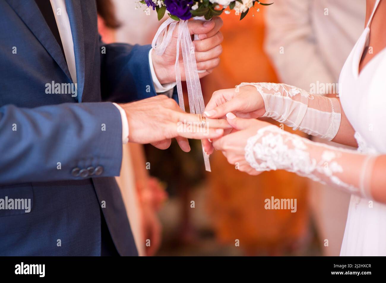 Wedding ceremony. Bride putting a golden ring on groom's finger closeup
