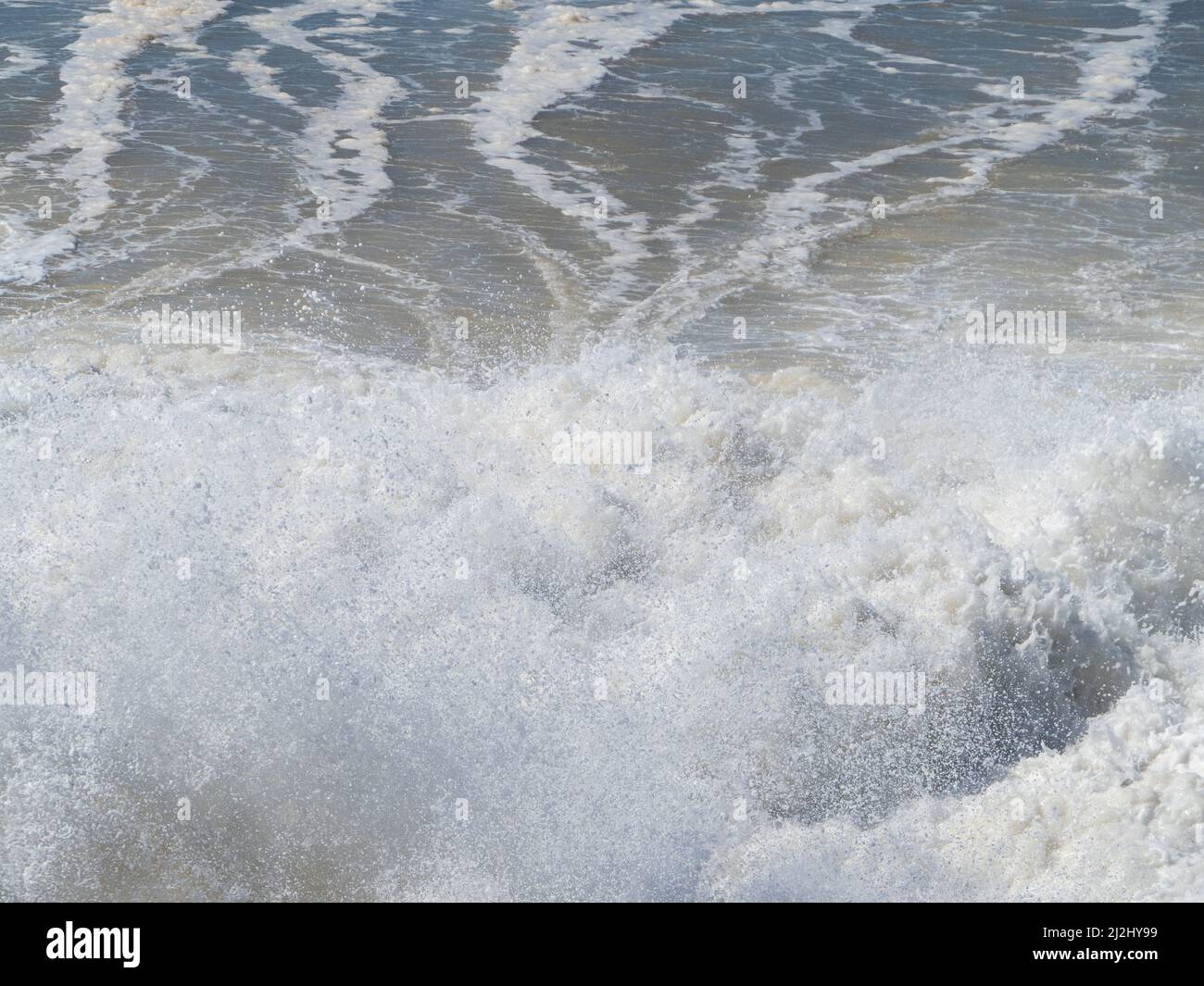 Closeup of Ocean waves crashing on rocks on shore, splashing, sea spray up, leaving swirly natural line patterns in the salty water, force of nature Stock Photo