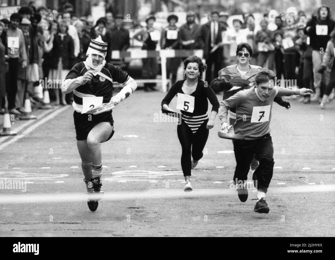 Sandwell Mail Pancake Race in west Bromwich High Street.Number 222, gary Lockley of the MacDonalds Team, all bandaged up on the way to winning the race with number 7, John West of NatWest Bank and in the centre  Jeanette Robert of Curves. Right at the back is Julie Ledbury of Marks and spencers. 3rd March, 1987 Stock Photo