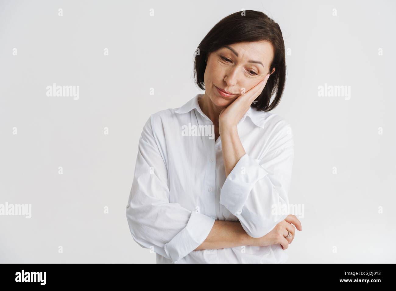 European mature woman propping up her head and looking downward ...