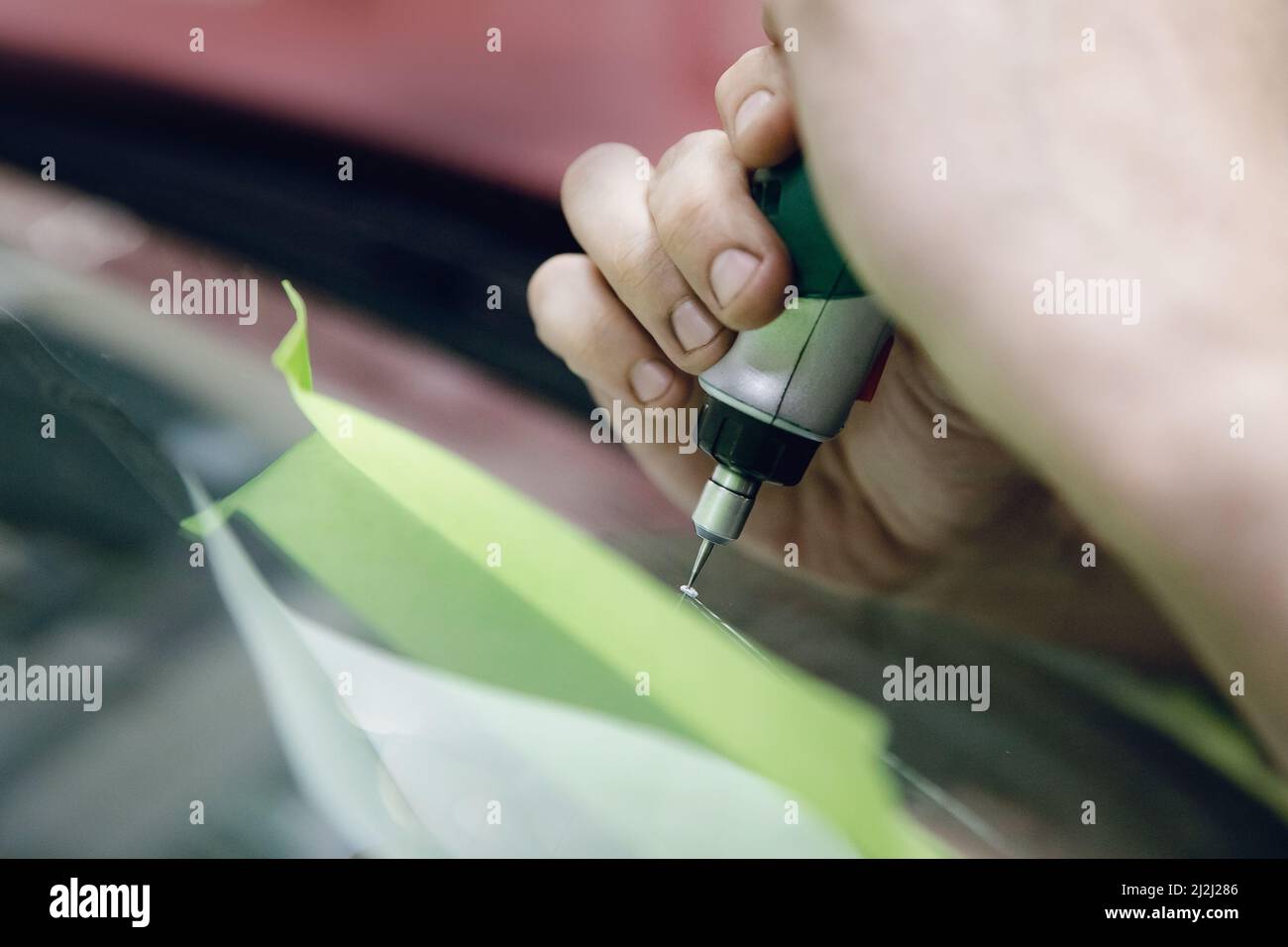 Worker fixes crack in car windshield, drills and pours epoxy Stock