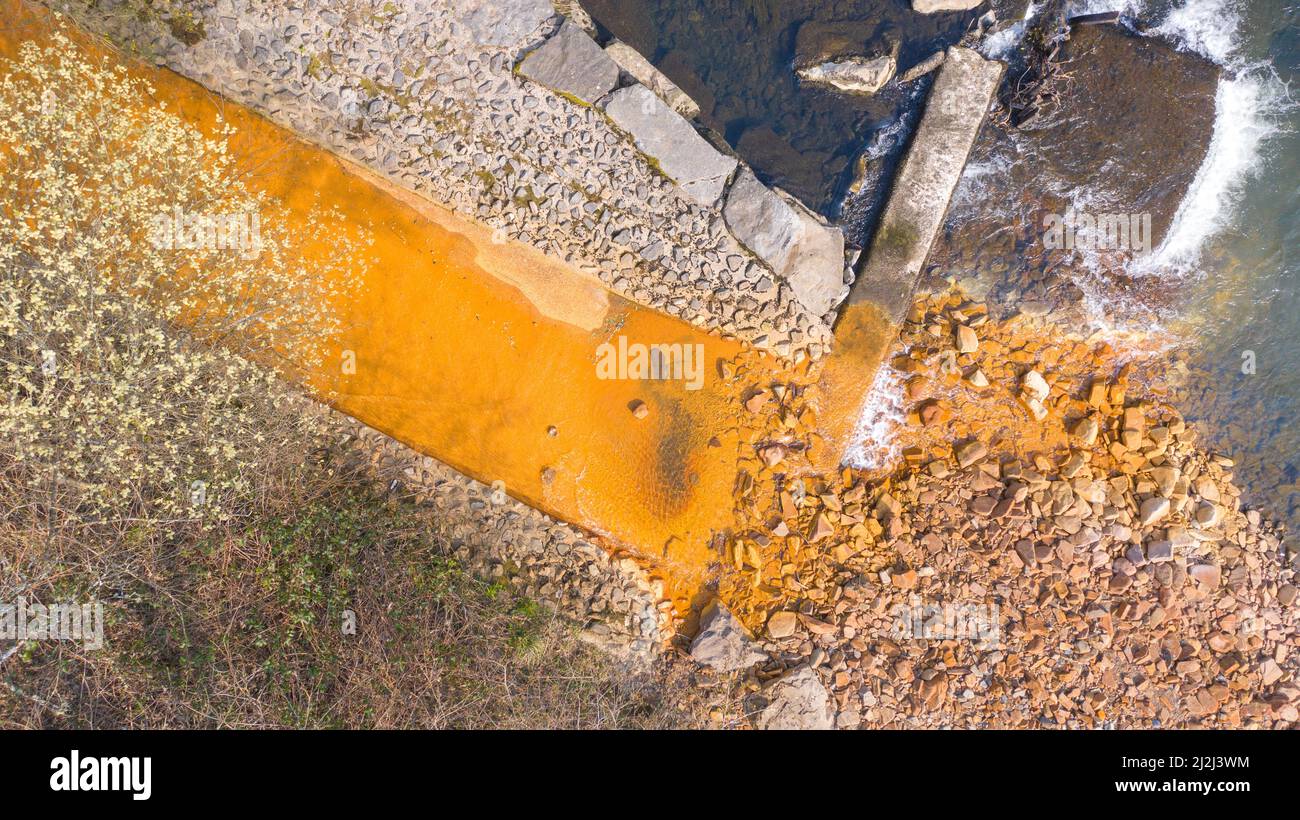 Aerial view of orange iron oxide staining in stream entering River