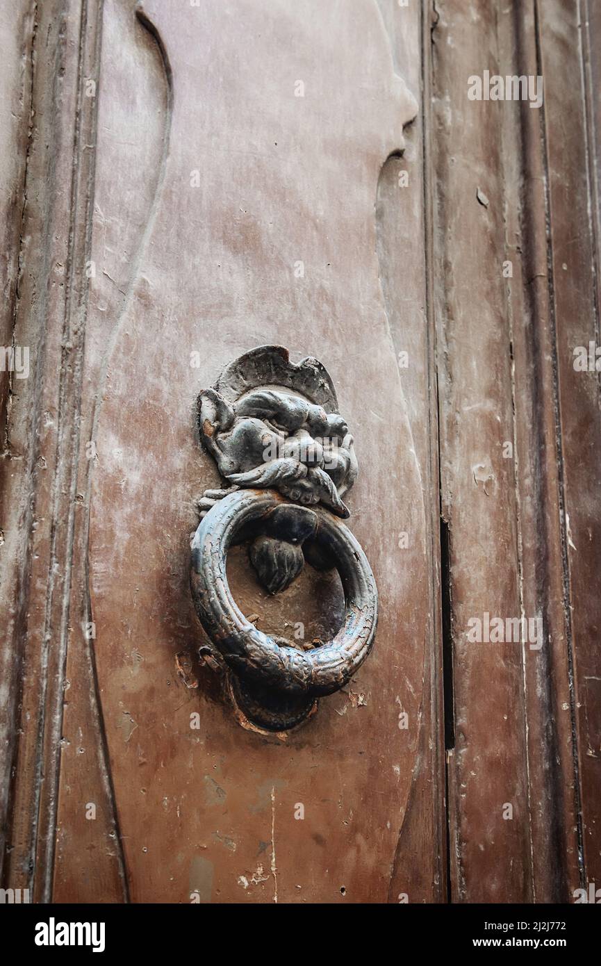 door with a brass knocker in the shape of a man's head, a beautiful entrance to the house. Wooden door, detail. Decorative element. a door handle in Stock Photo