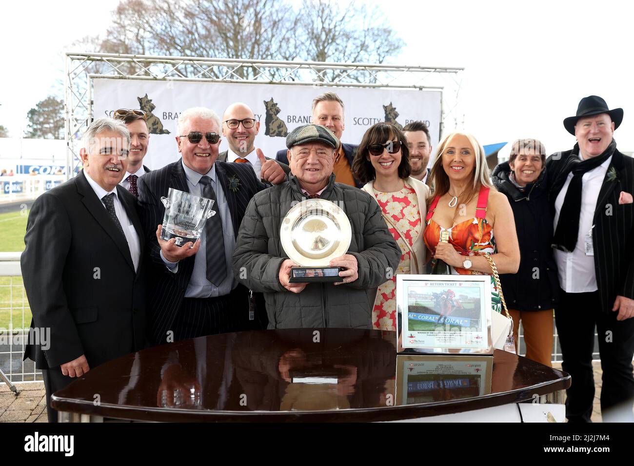 Trainer John Wade (centre) celebrates with the trophy after Return Ticket ridden by jockey Sean Quinlan wins the Scotty Brand Handicap Chase during the Coral Scottish Grand National day at Ayr Racecourse, Ayr. Picture date: Saturday April 2, 2022. Stock Photo