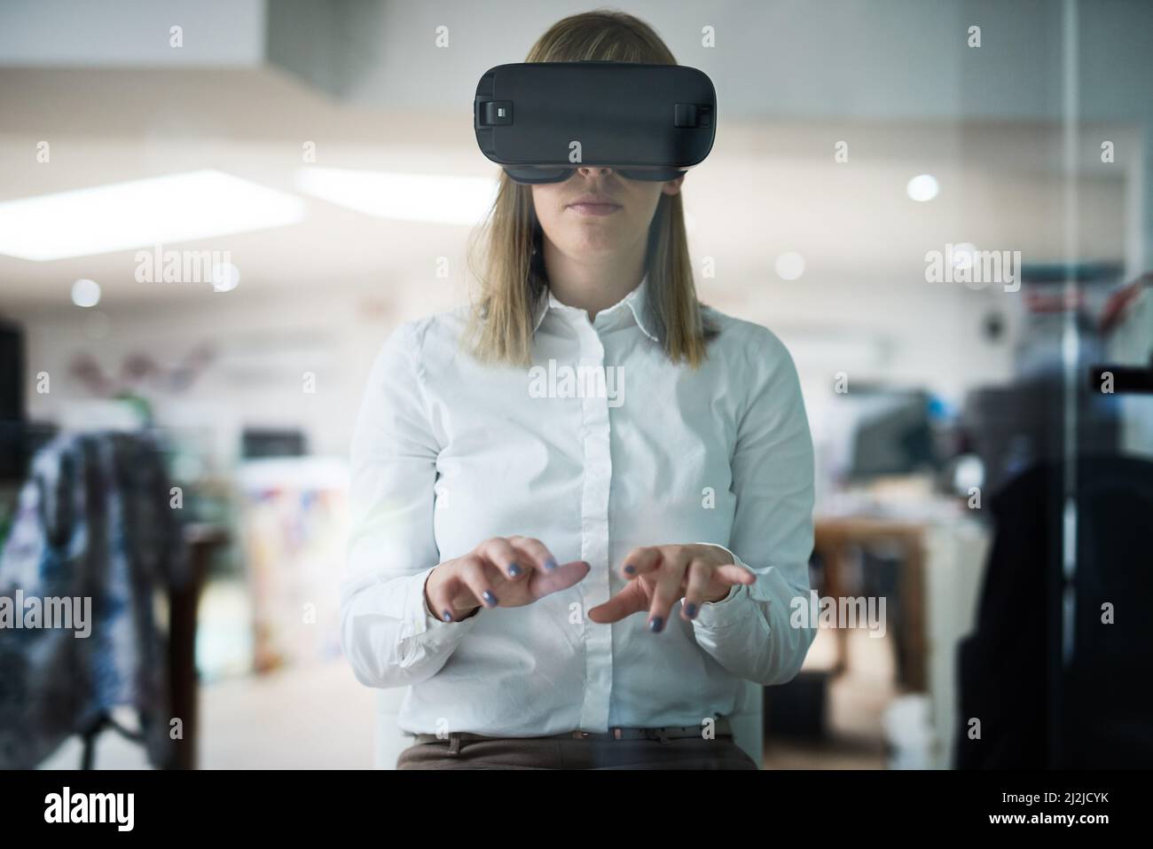 Business only moves forward when it embraces technology. Multiple exposure shot of a young businesswoman wearing a VR headset while working alone in Stock Photo