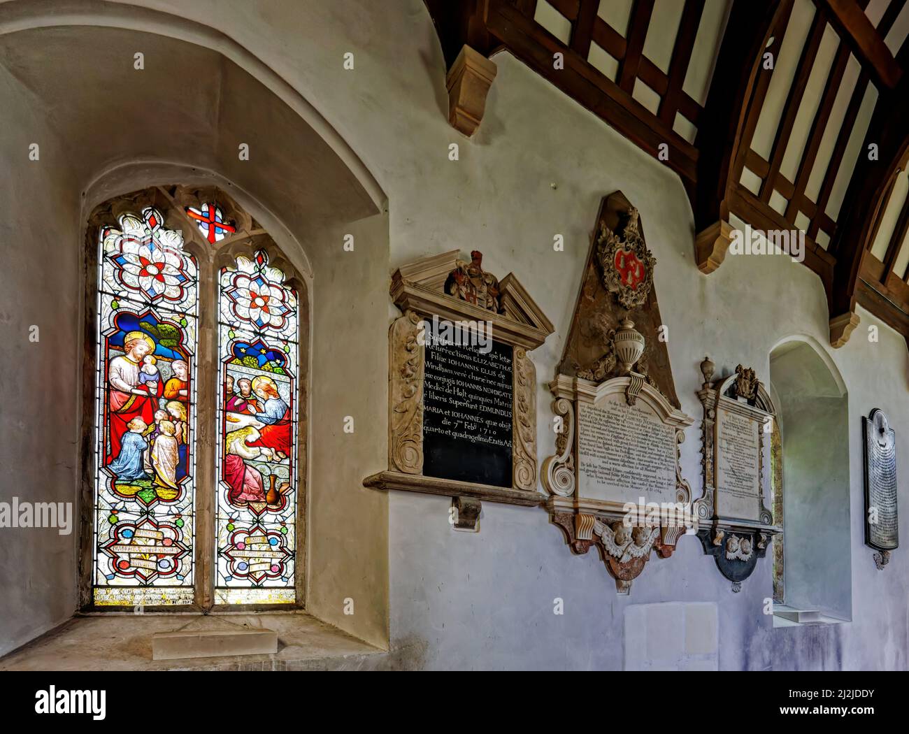 View of stained glass window and church monuments inside the parish Church of St Andrew the Apostle in Holt, a historic town in north Norfolk, England Stock Photo