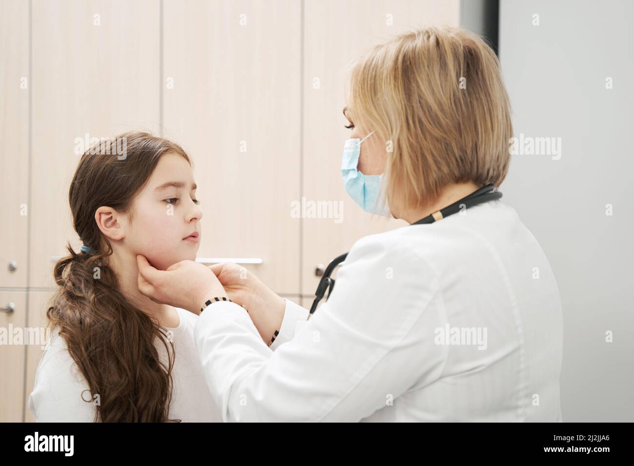 Female pediatrician examining child lymph nodes in clinic Stock Photo
