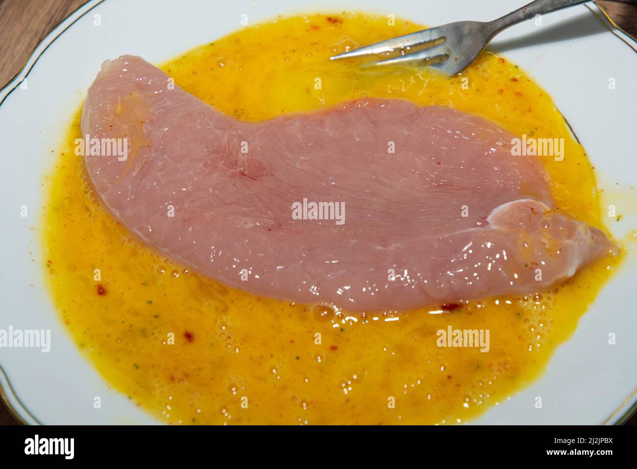 Turkey escalopes in egg yolk for breading Stock Photo Alamy