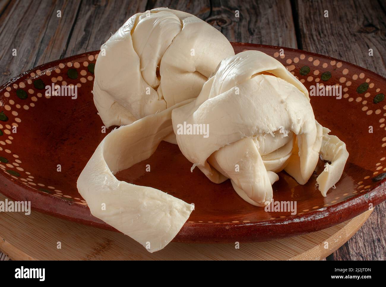 QUESILLO, on a mud or clay plate over a round chopping board, a