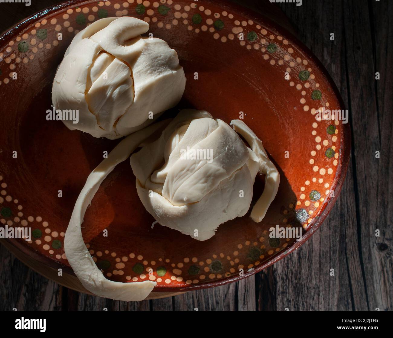 QUESILLO, on a mud or clay plate over a round chopping board, a ...