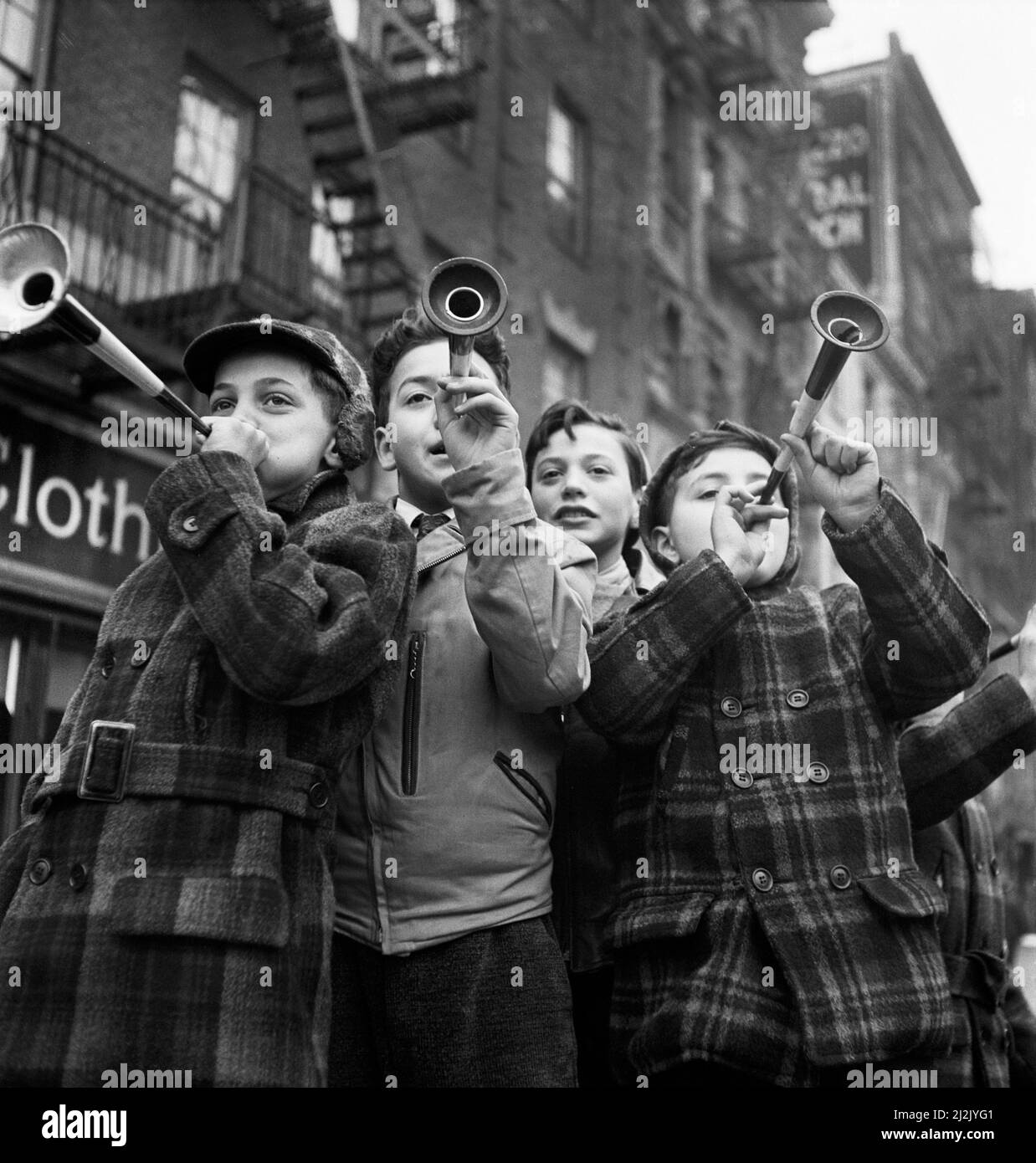 Four Boys blowing horns on New Year's Day, Bleecker Street, New York City, New York, USA, Marjory Collins, U.S. Office of War Information/U.S. Farm Security Administration, January 1943 Stock Photo