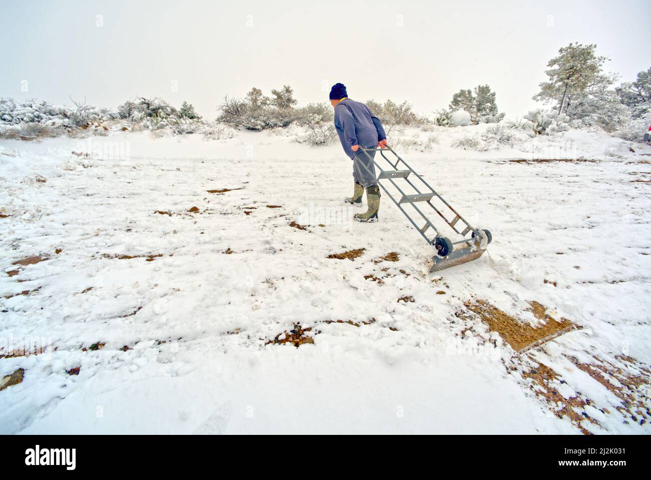 Man using an upside down appliance Dolly to clear snow, Chino Valley, Arizona, USA Stock Photo