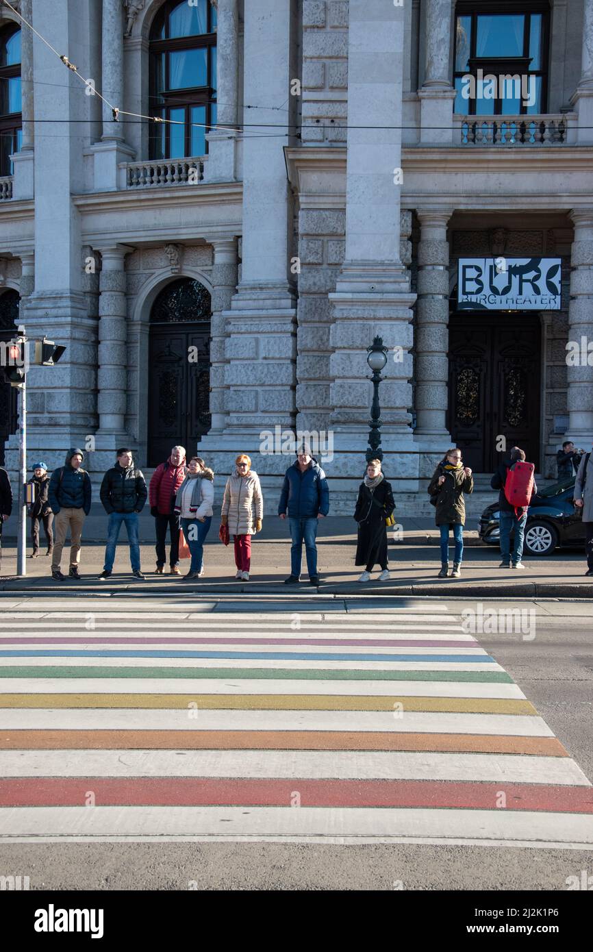 Pedestrians waiting to cross on the rainbow crosswalk outside of Burgtheater, Vienna, Austria, December 11, 2019. Stock Photo
