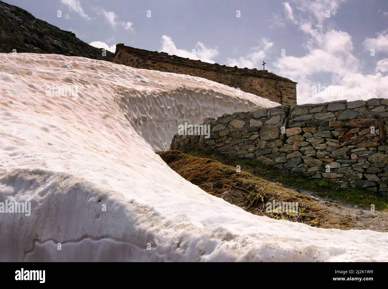 Snow drift next to a church, Great St Bernard Pass, Switzerland Stock Photo