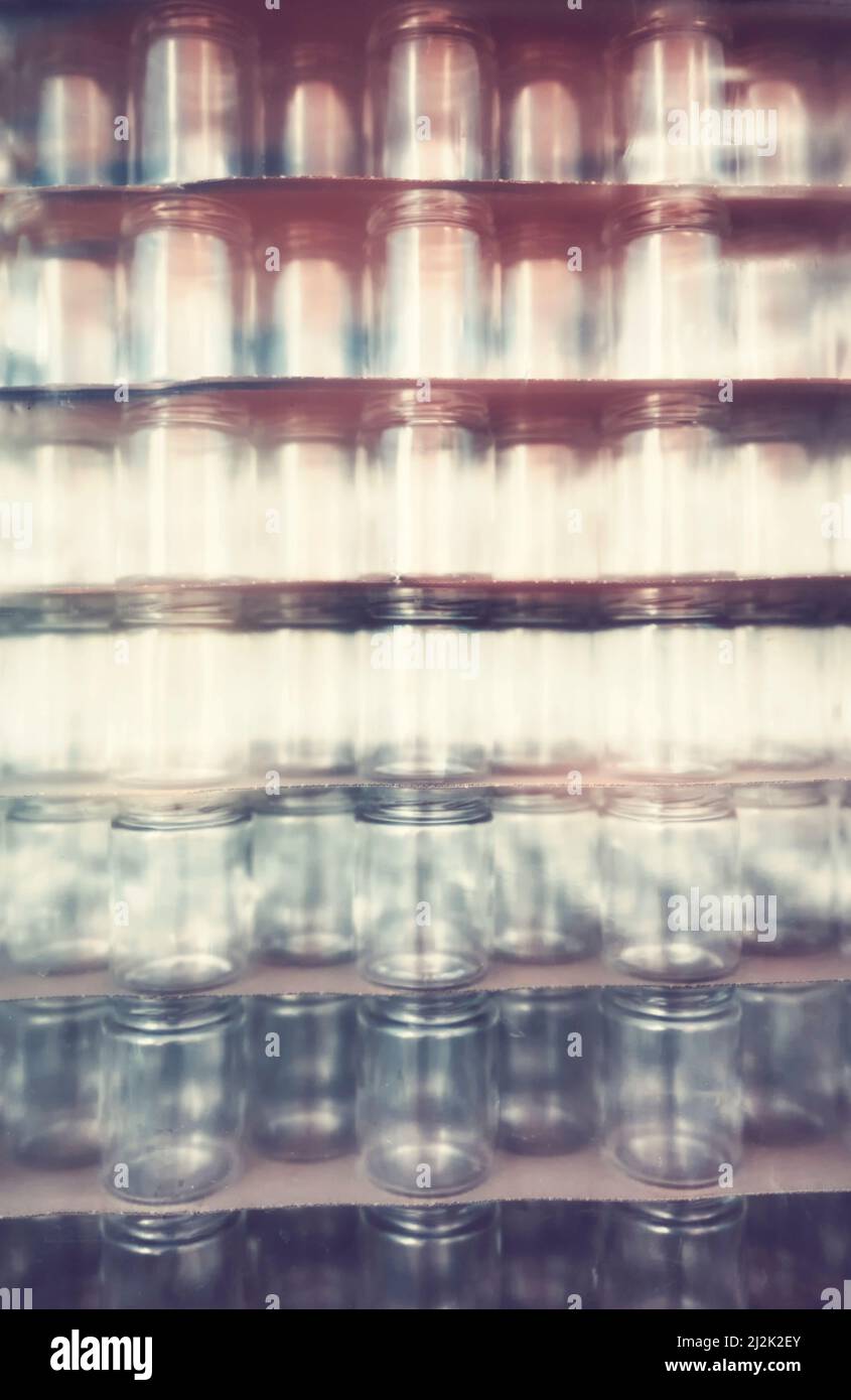 Blurred glass jars covered with plastic, abstract background. Stock Photo