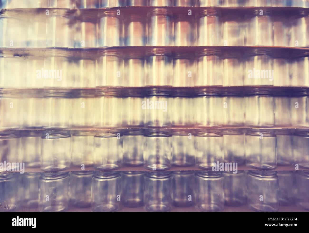 Blurred glass jars covered with plastic, abstract background. Stock Photo