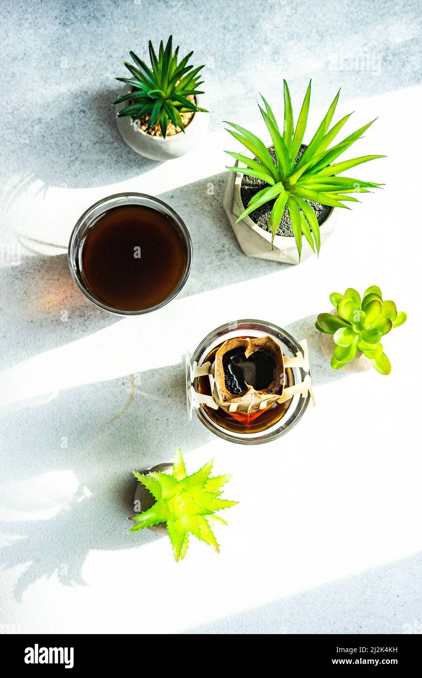 Overhead view of a glass of coffee, individual coffee filter and