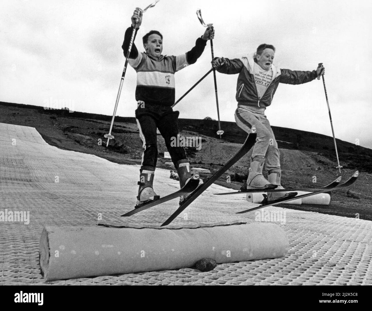 Children practising their ski-jumps on their self made jumps while the permanent jumps are under construction. Snowtrail, who own the slope, are currently extending the slopes from 200 metes to over 350 metres. Merthyr Ski Slope centre. Circa 1988. Stock Photo