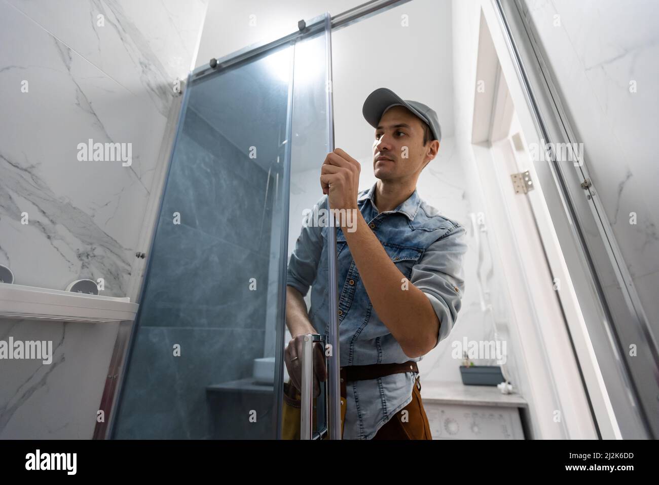 Workers are installing glass door of the shower enclosure Stock Photo Alamy